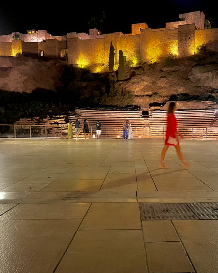 La Alcazaba iluminada y el teatro romano de noche vistos desde la calle Alcazabilla en el casco antiguo de Málaga