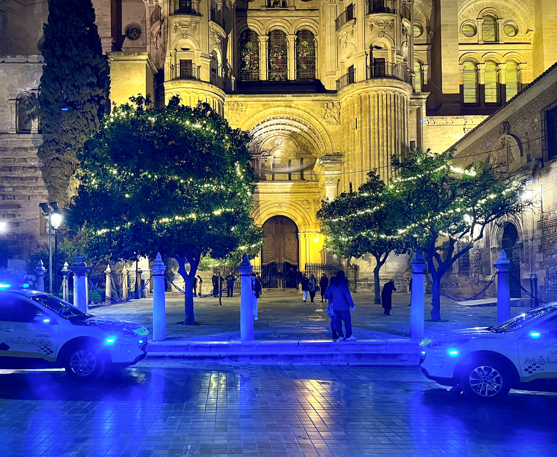 La catedral de Málaga iluminada por luces de policía en Nochebuena, en el casco antiguo de Málaga