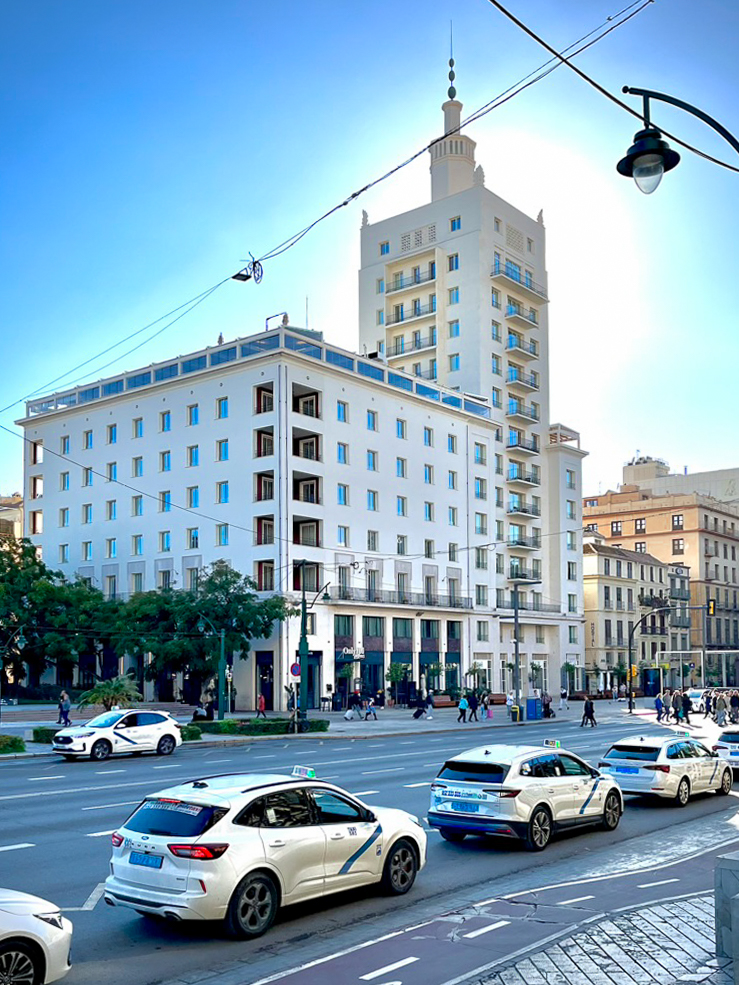 Edificio La Equitativa en Málaga, sede del hotel Only YOU y Soho Boutique, en la Alameda Principal al atardecer, con una fila de taxis delante