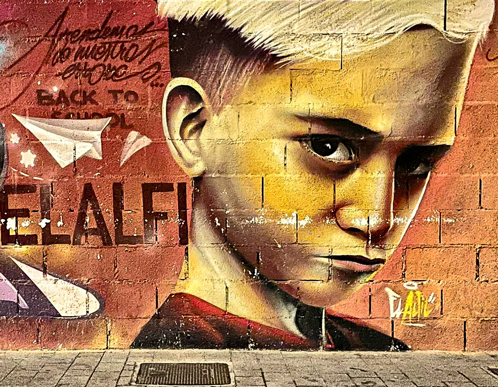 “Back To School” mural depicting an unhappy looking boy by El Alfil in Málaga’s Lagunillas district