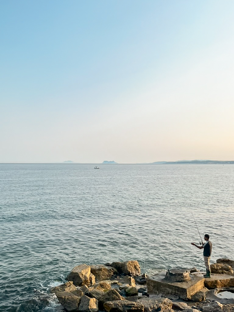 Hombre pescando al atardecer en Estepona con Gibraltar en el horizonte
