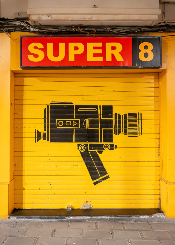 La persiana metálica de seguridad cerrada del Súper 8 Club en Almería, con un sencillo mural de la silueta de una cámara de cine retro