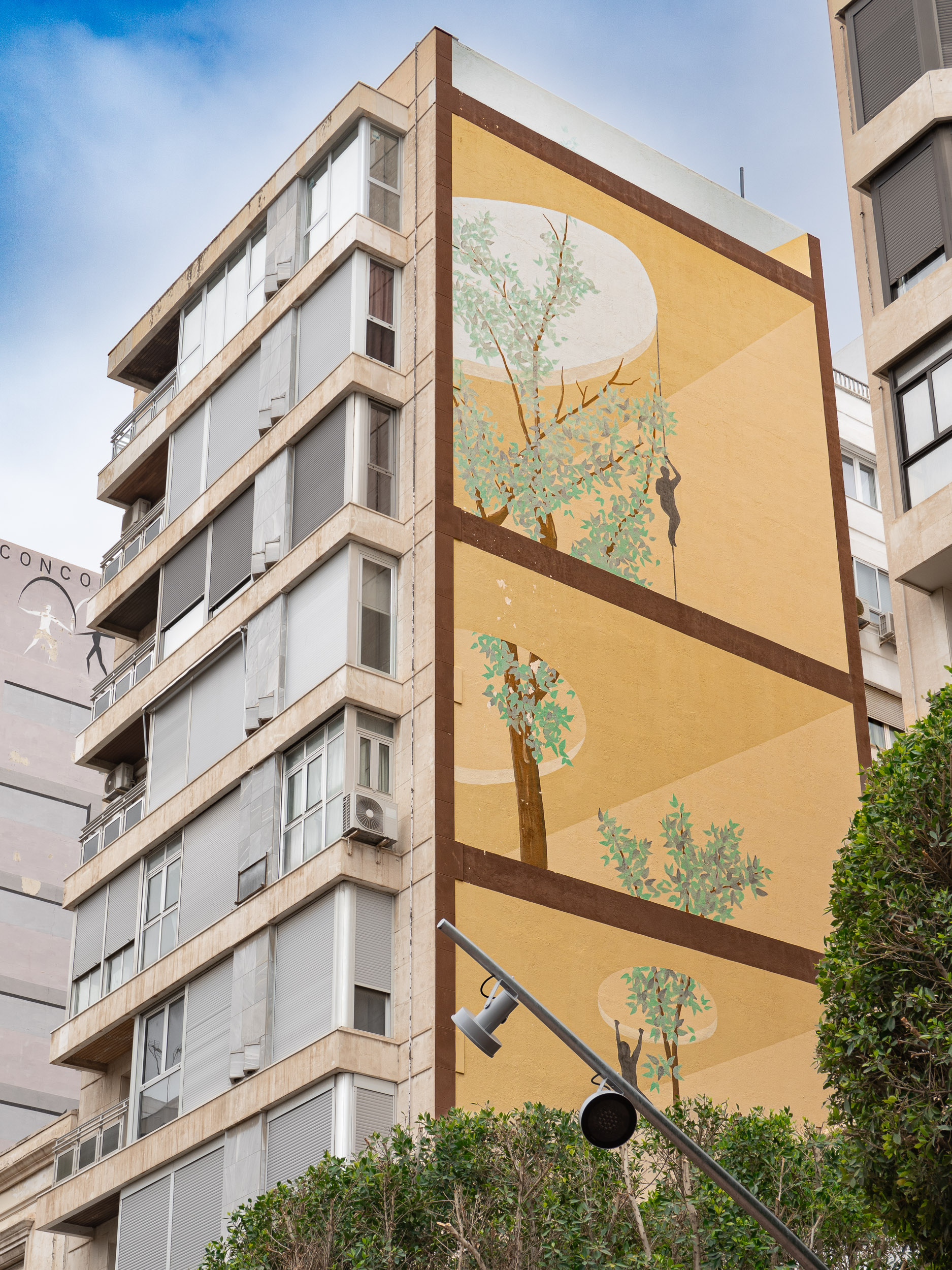 Large mural of trees and a climbing figure on an apartment building along Avenida Federico García Lorca in Almería