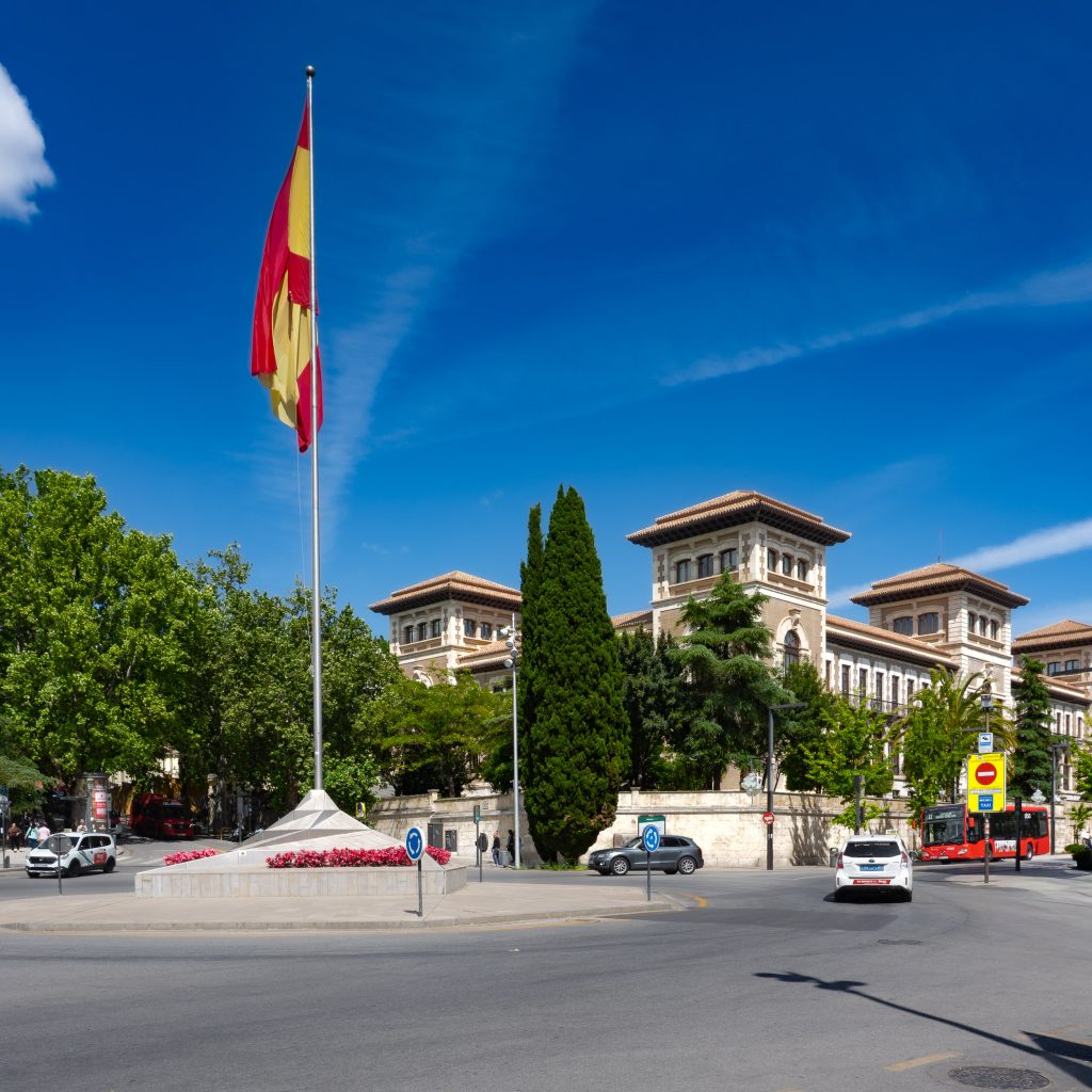 Rotonda con bandera española en la Avenida de la Constitución con la Delegación Territorial de Educación de Granada