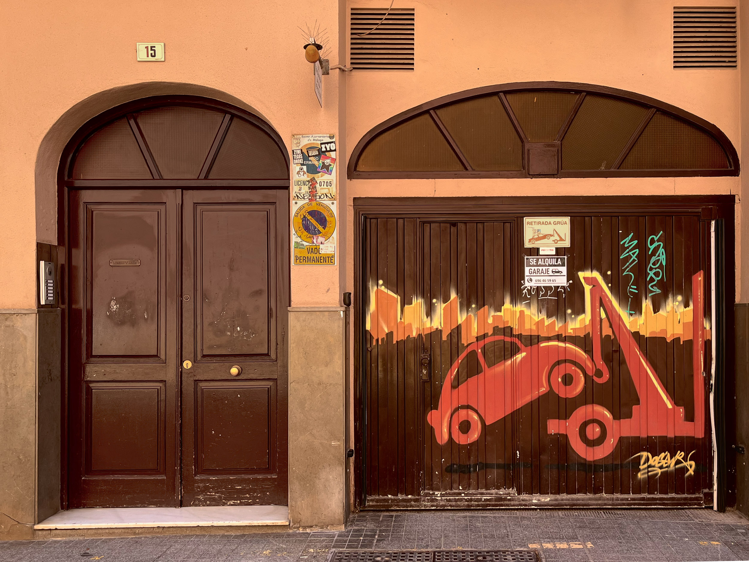 Graffiti by Doger with the message "Tow Truck Removal" on a garage door, depicting a car being towed