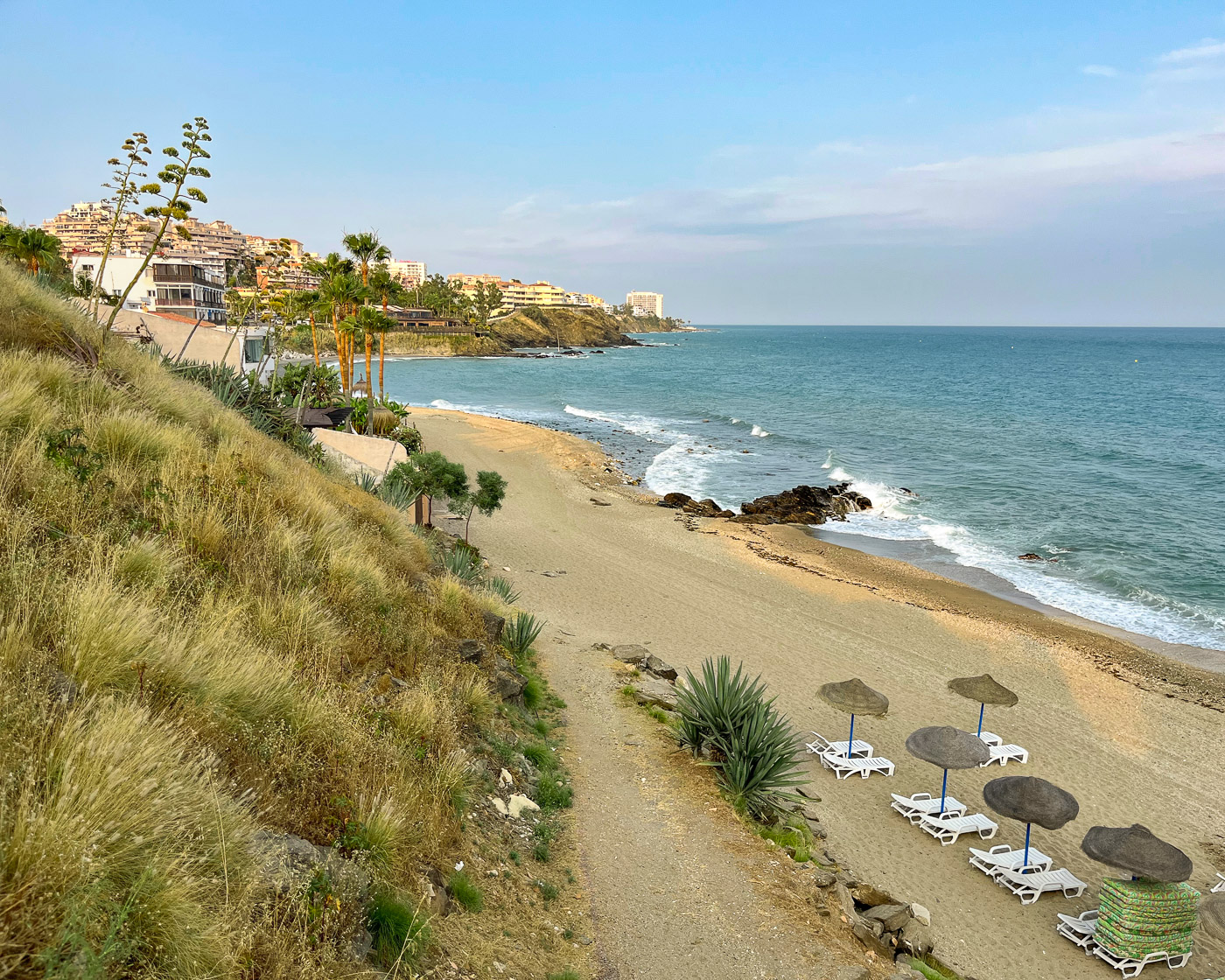 Snorkeling spot at Playa Bonita on the Carretera de Cádiz in Benalmádena at sunset, with beach hotels and rocks in the background