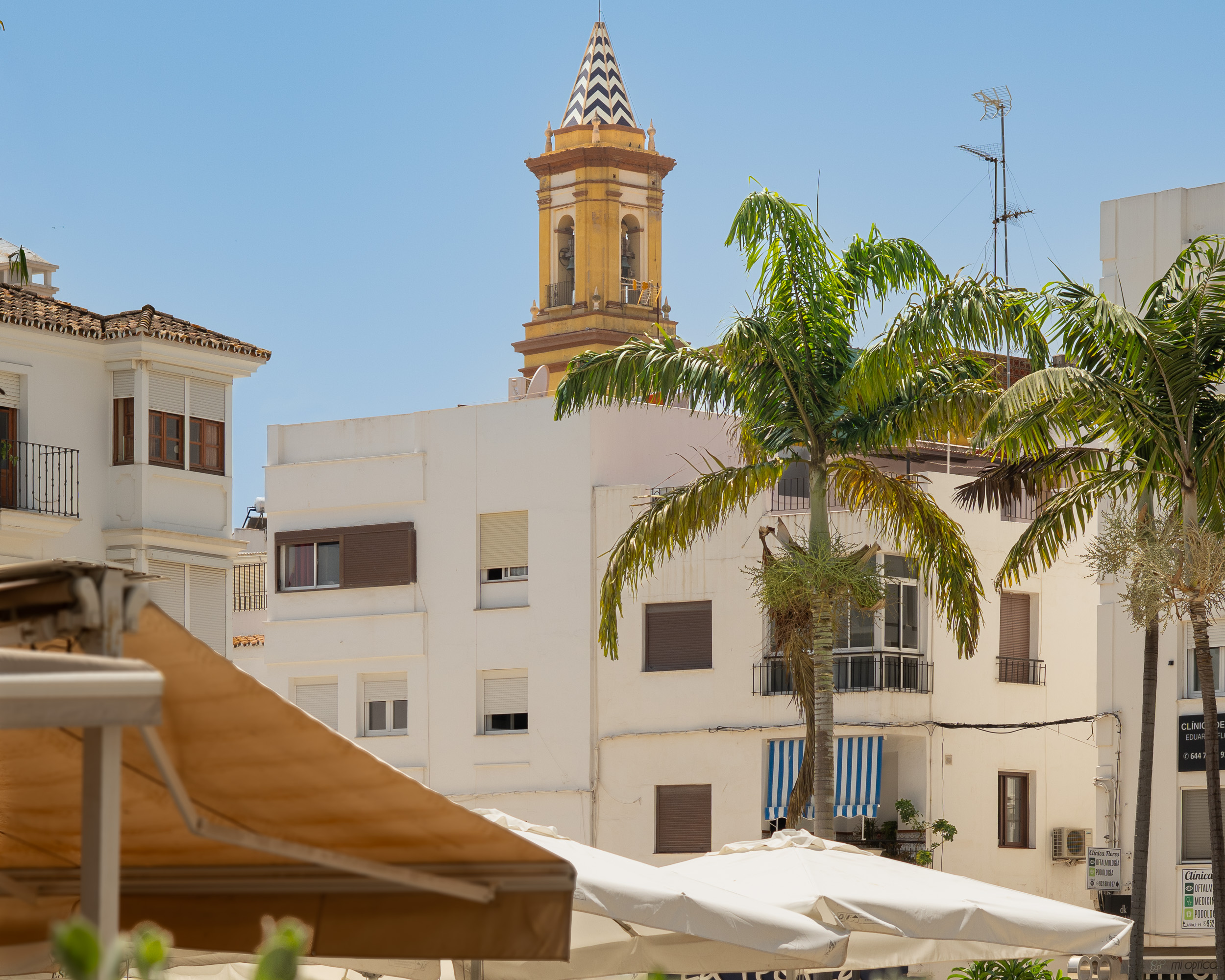 La iglesia de Los Remedios, palmeras y sombrillas en Estepona