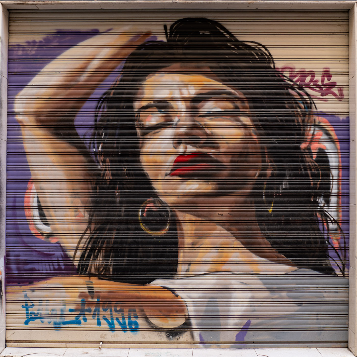 Mural de Raúl Ruiz, El Niño de las Pinturas, de una mujer en una persiana en Calle Navarrete en Granada