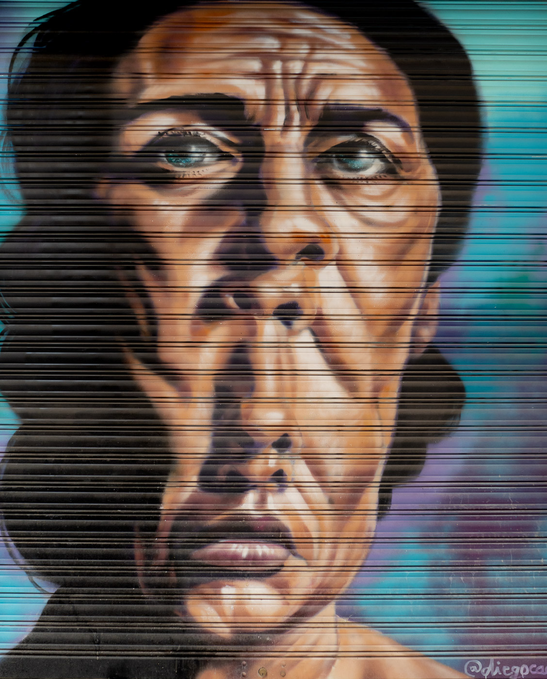 Mural surrealista de un rostro, obra de Diego Cacamut, pintado en una persiana metálica en la calle Navarrete de Granada