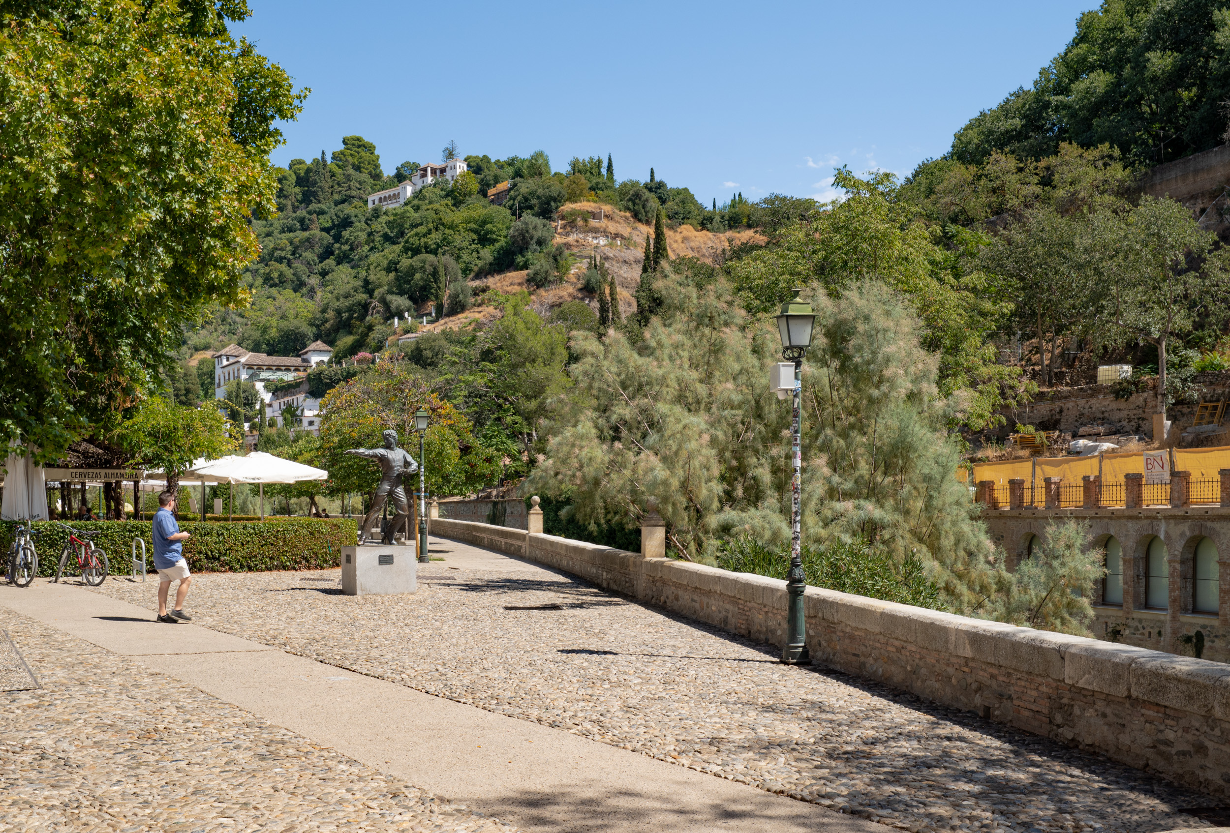 Paseo de los Tristes in Granada's Albaicín neighbourhood, along the Darro River, with the bronze statue of the renowned flamenco dancer Mario Maya in the foreground