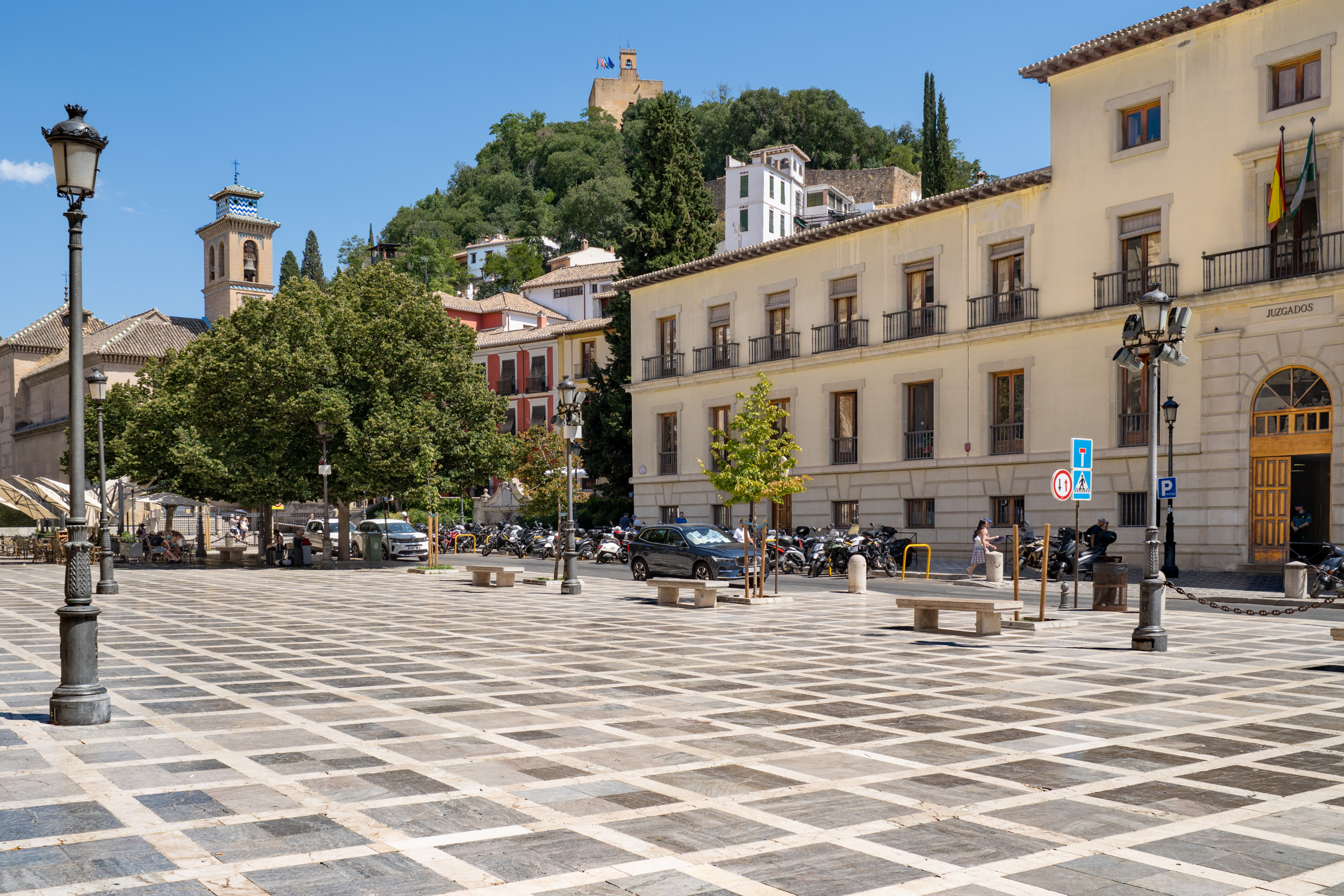 Plaza Nueva, with the courthouse, a church, and the Alcazaba in the background, in Granada's Albaicín neighborhood